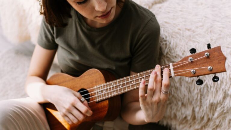 Kobieta siedzi przy łóżku gra na ukulele